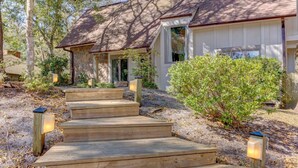 A house with a stone exterior, wooden steps, and a covered porch with a window.