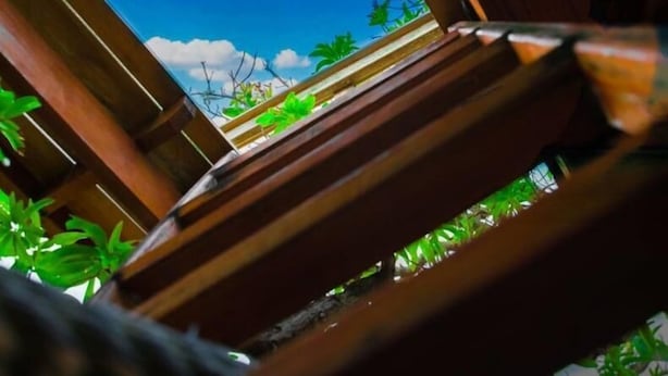 Une structure en bois offrant une vue sur un ciel bleu dégagé et sur quelques espaces verts.