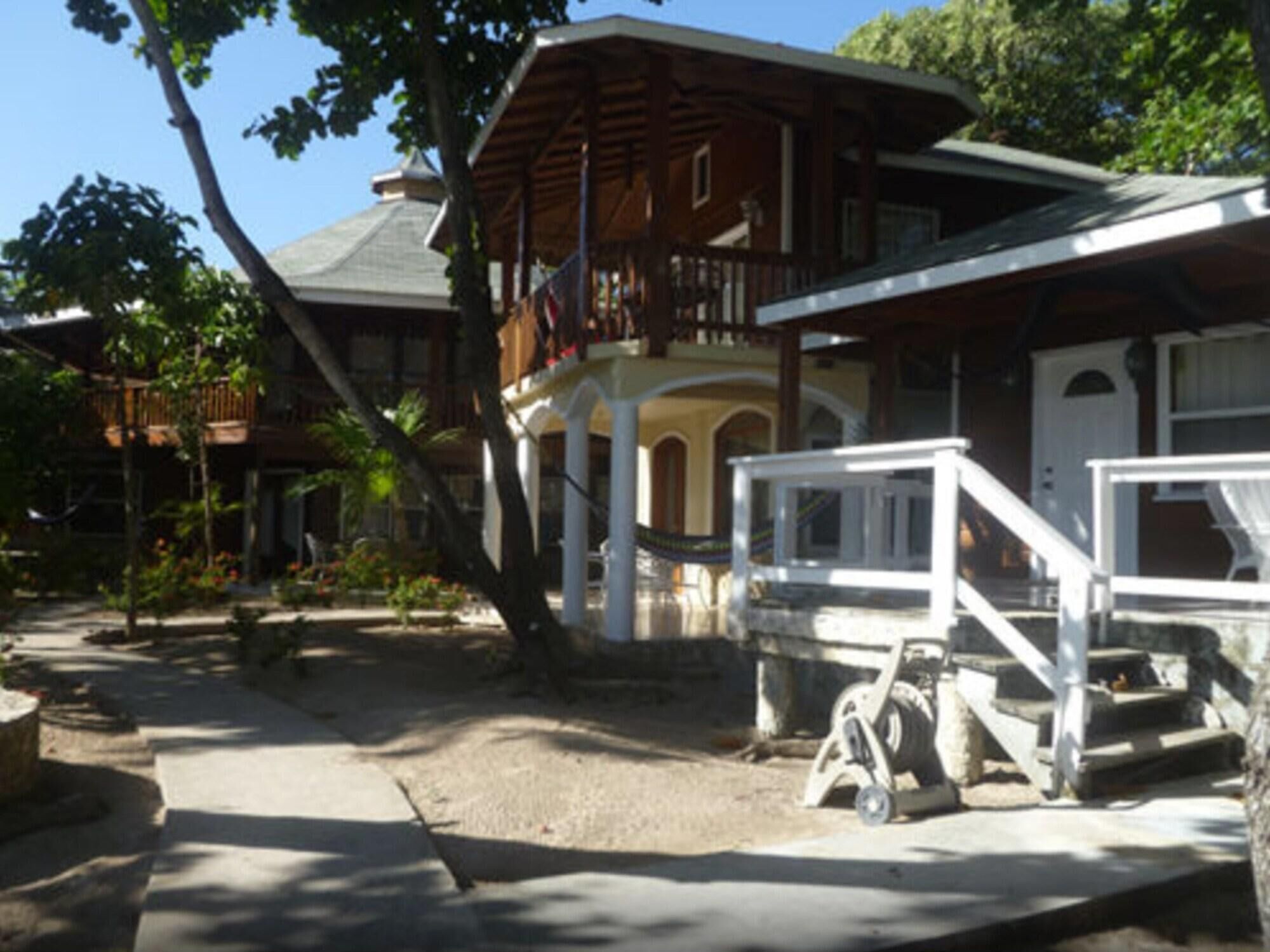 Ein zweistöckiges Holzhaus mit Balkon, Veranda und einer Treppe, die zum Eingang führt.