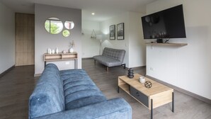 A modern living room with a grey sofa, a wooden coffee table, a TV mounted on the wall, and a grey armchair. - 3 Bed 2.5 Bath Modern Apartment in Laureles (Medellín)