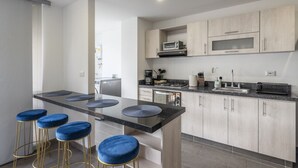 A modern kitchen with a central island, bar stools, and built-in appliances. - 3 Bed 2.5 Bath Modern Apartment in Laureles (Medellín)