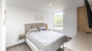 A bedroom with a bed, bedside table, lamp, and a TV mounted on the wall. - 3 Bed 2.5 Bath Modern Apartment in Laureles (Medellín)