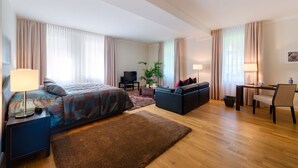 Une chambre d’hôtel équipée d’un lit, d’un bureau, d’une chaise, d’un canapé, d’une télévision et d’une plante.
