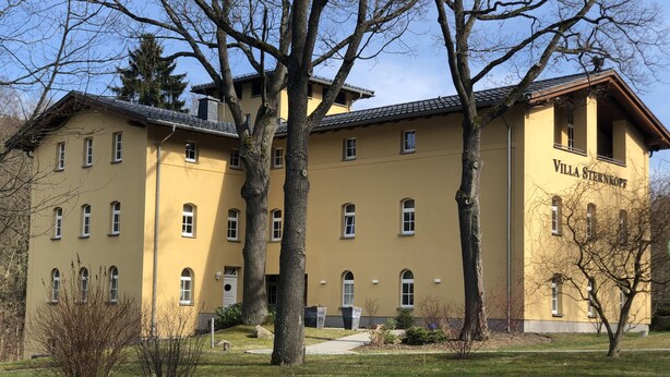 Un bâtiment jaune appelé Villa Sternkopf, doté de nombreuses fenêtres et d’un toit plat.