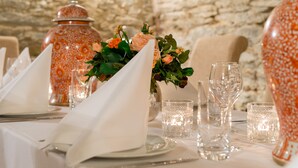 Une table dressée avec des serviettes blanches, de la vaisselle transparente et un vase rempli de fleurs.
