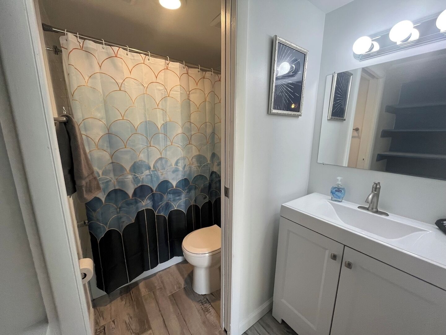 A bathroom with a toilet, a sink, a mirror, and a shower curtain with a scalloped pattern.