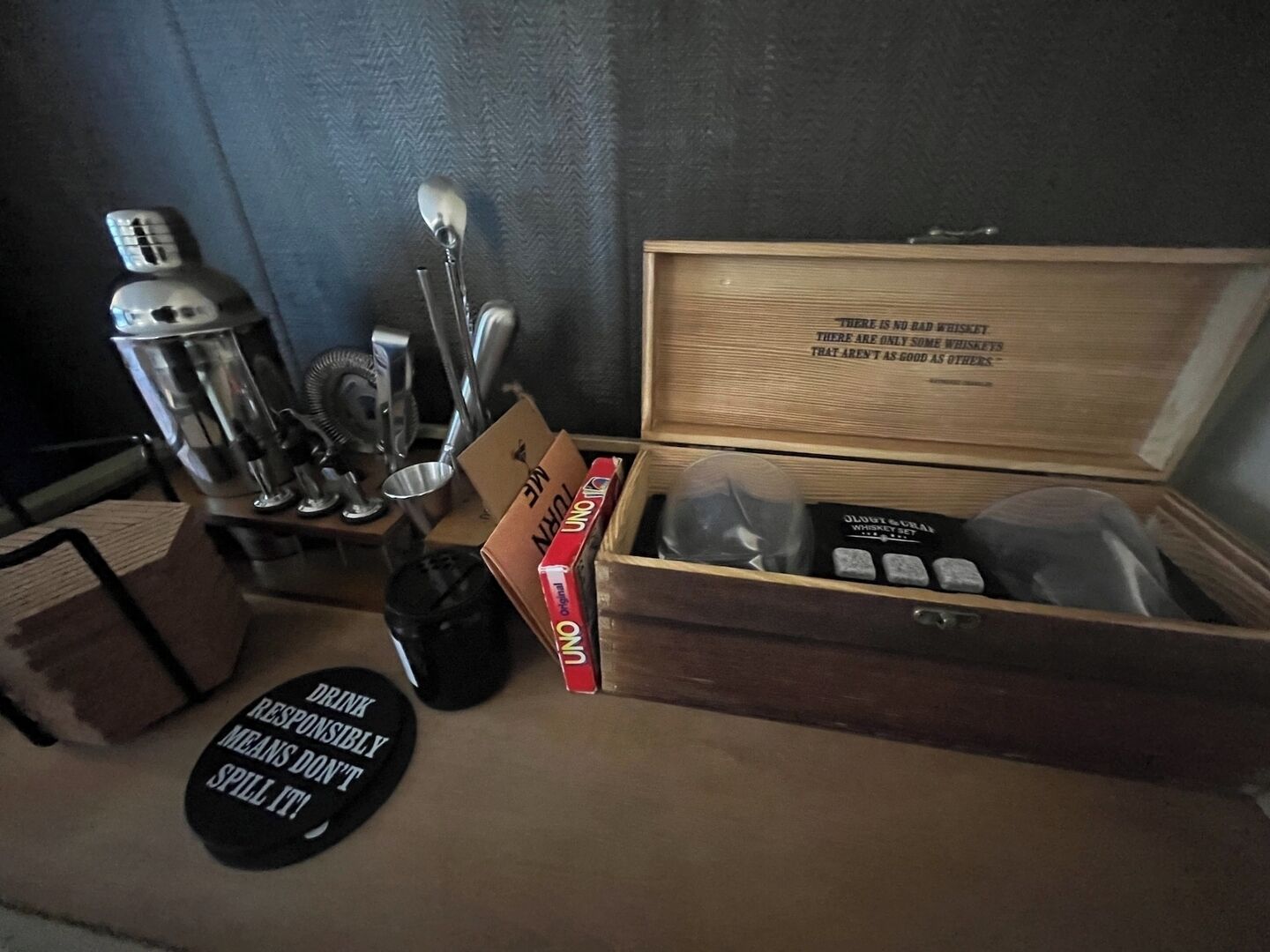 A wooden box with a quote, a bottle, a spoon, and a coaster with a message.