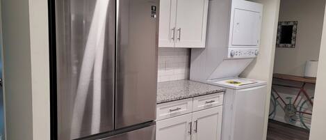 A compact kitchen with stainless steel appliances, white cabinetry, and a built-in washing machine.
