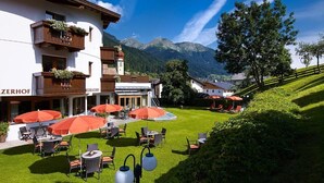 A hotel with outdoor seating, a mountain view, and a well-maintained lawn. - Medrazerhof (Fulpmes)