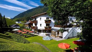 A hotel with a terrace, outdoor seating, and a mountain backdrop. - Medrazerhof (Fulpmes)