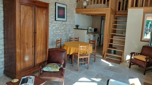 Ein gemütliches Wohnzimmer mit einem Holzkabinett, einem Esstisch mit Stühlen, einer Treppe und einer Küchenzeile im Hintergrund.