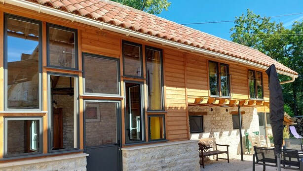 Ein Holzhaus mit vielen Fenstern und einer Steinwand.