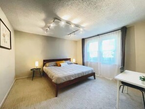 Relax in this serene bedroom with a large bed, bedside tables, and a window with curtains.