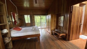 Une pièce de style cabane en bois, avec un lit, une petite table et un ventilateur de plafond.