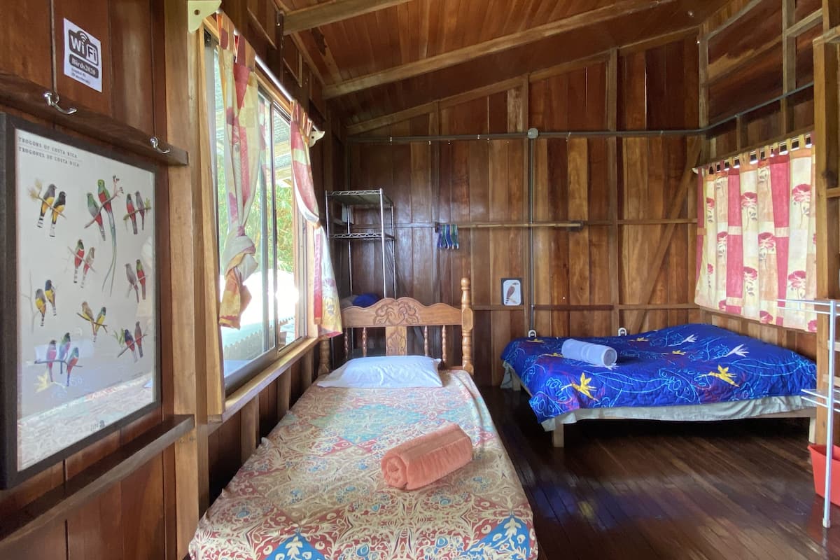 A wooden cabin with two beds, a wooden ceiling, and a poster of birds on the wall.