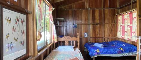 A wooden cabin with two beds, a wooden ceiling, and a poster of birds on the wall.