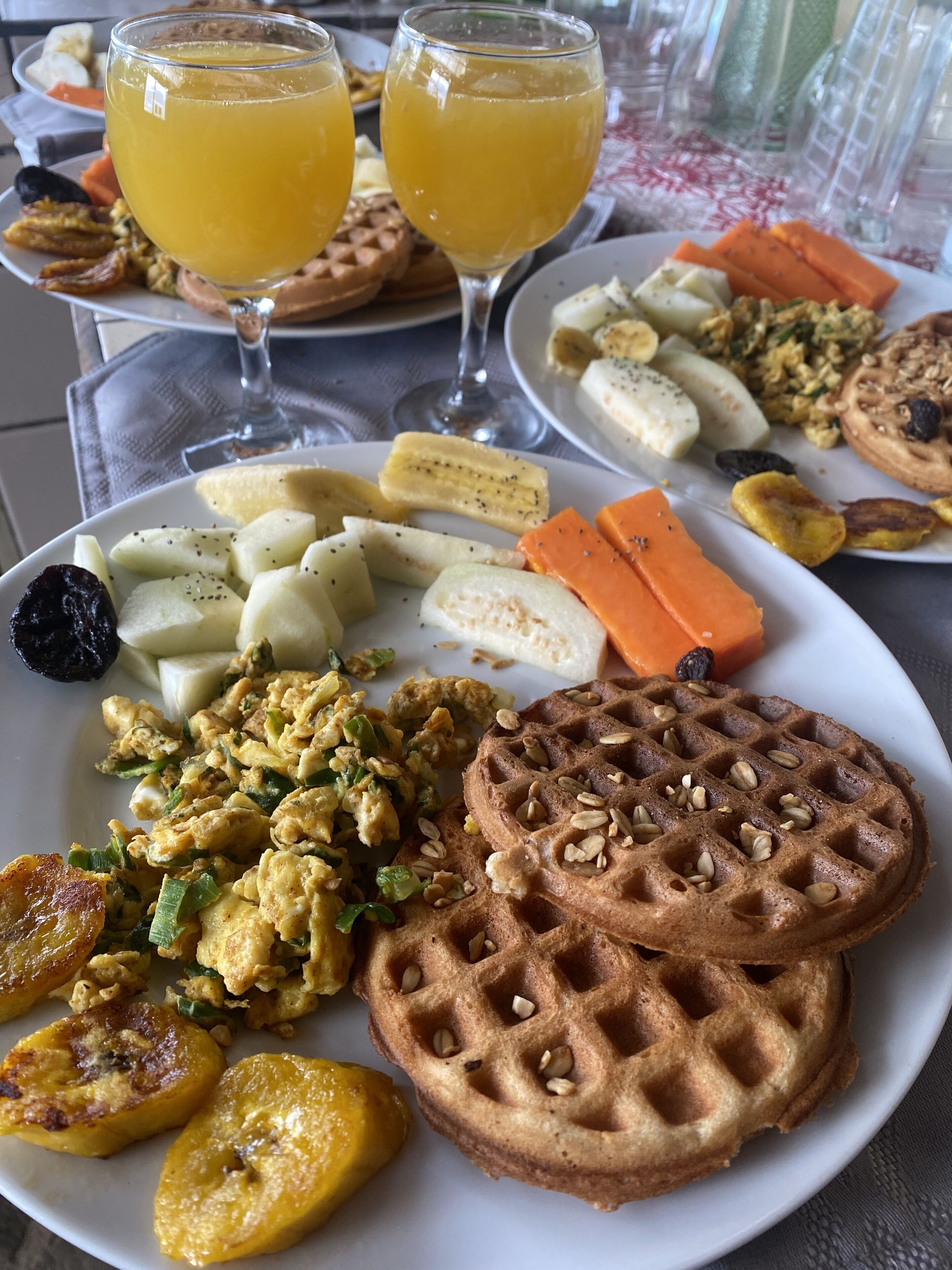 Une assiette de petit-déjeuner avec des gaufres, des œufs brouillés et des tranches de bananes.