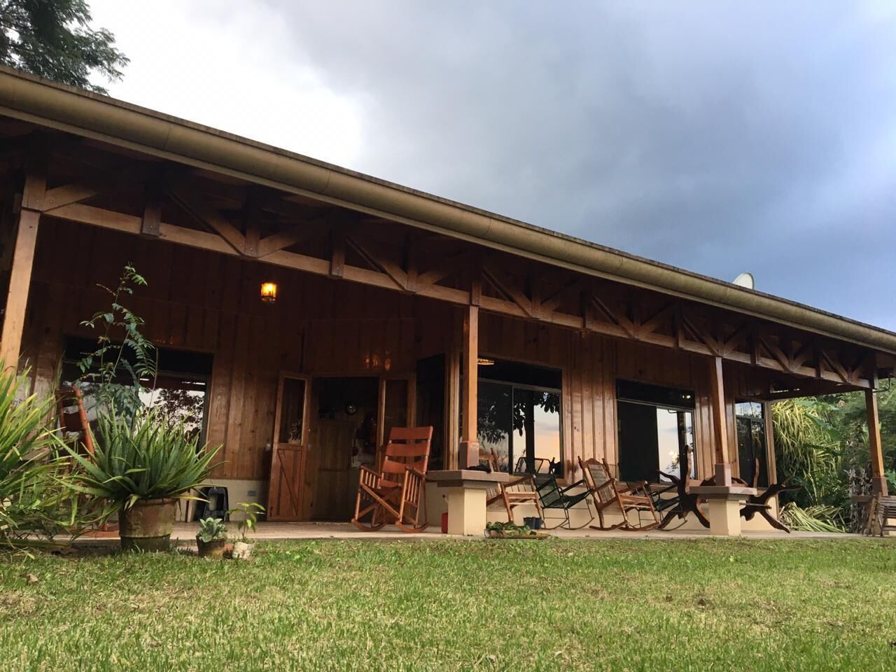 A wooden building with a covered porch, outdoor seating, and potted plants.