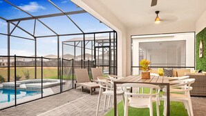 A modern outdoor patio with a glass enclosure, a hot tub, and a dining area with white furniture.