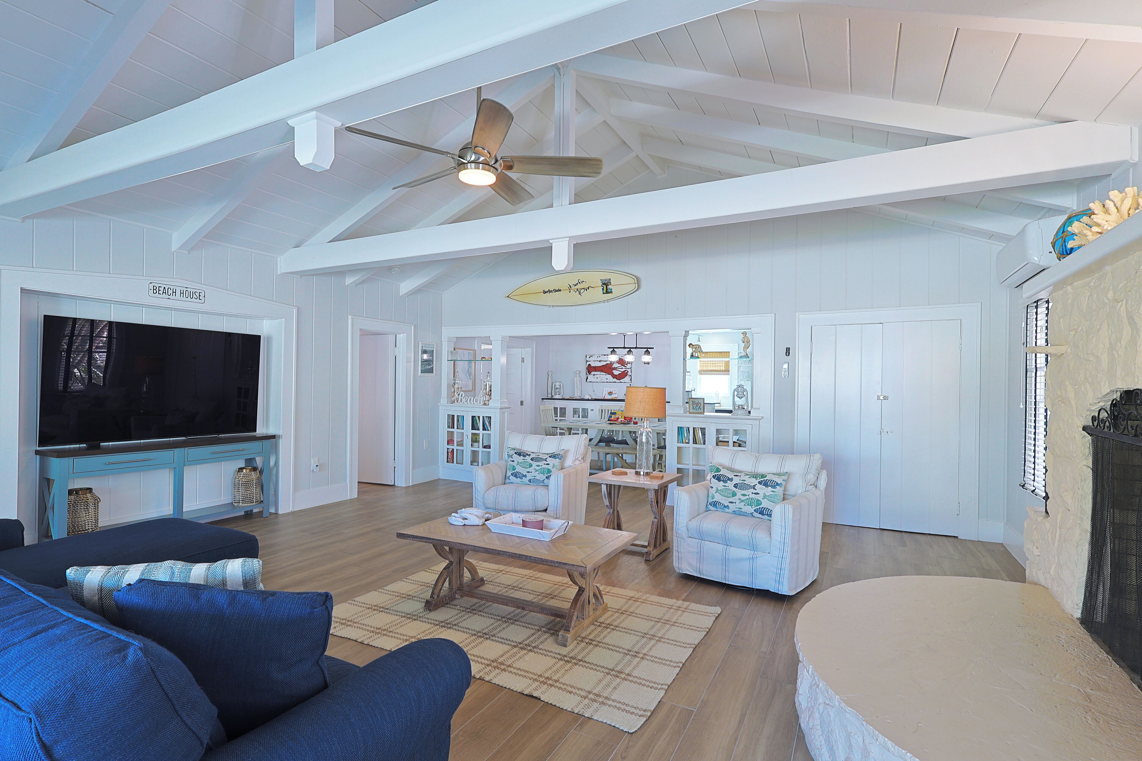 A spacious living room with a large TV, comfortable seating, and a ceiling fan.