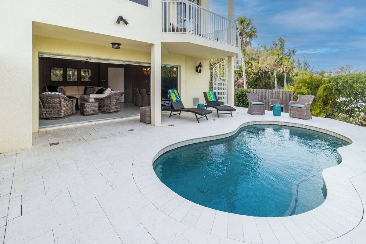 A residential property with a swimming pool, outdoor seating area, and a covered patio.