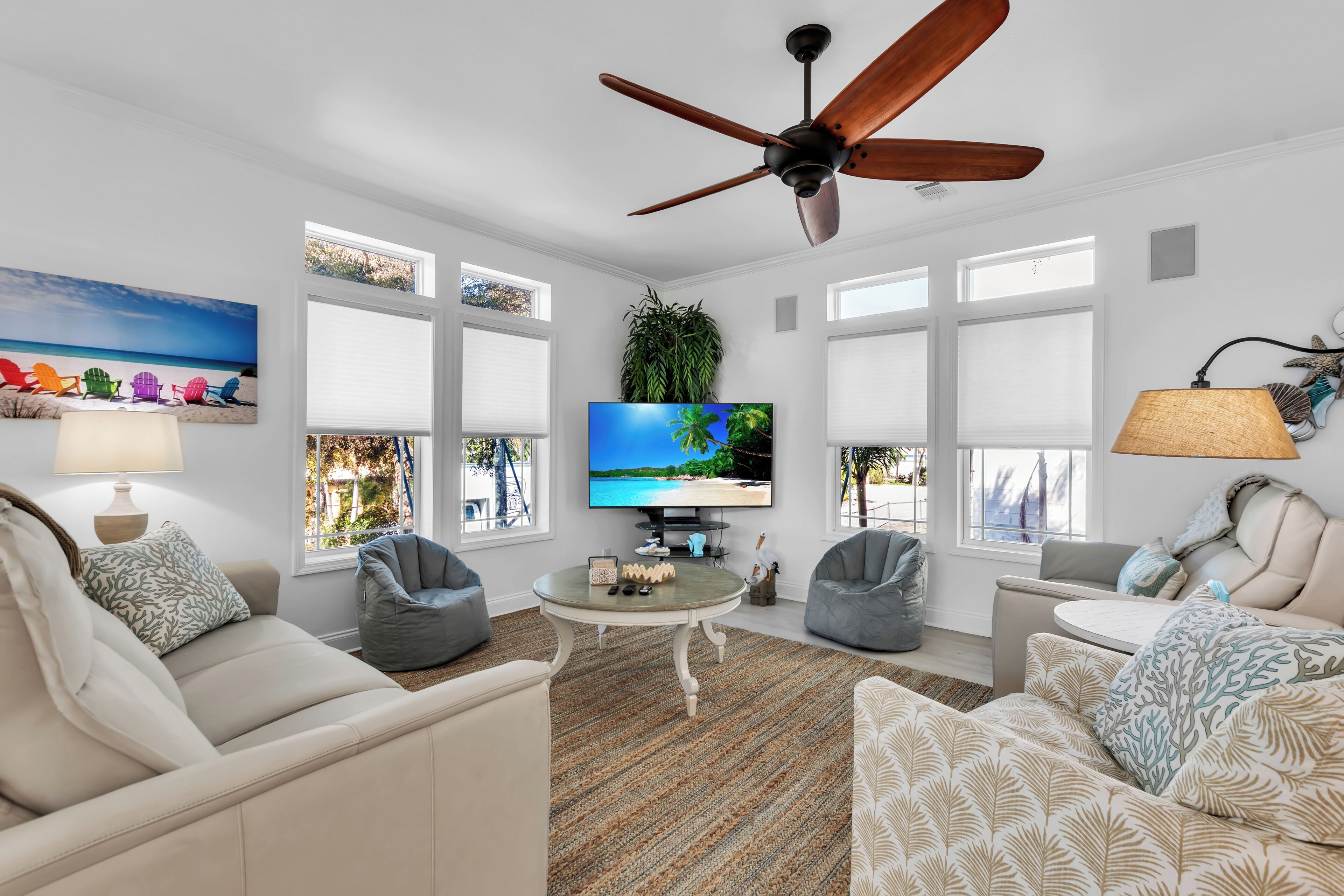 A living room with a ceiling fan, a TV, and a large window.