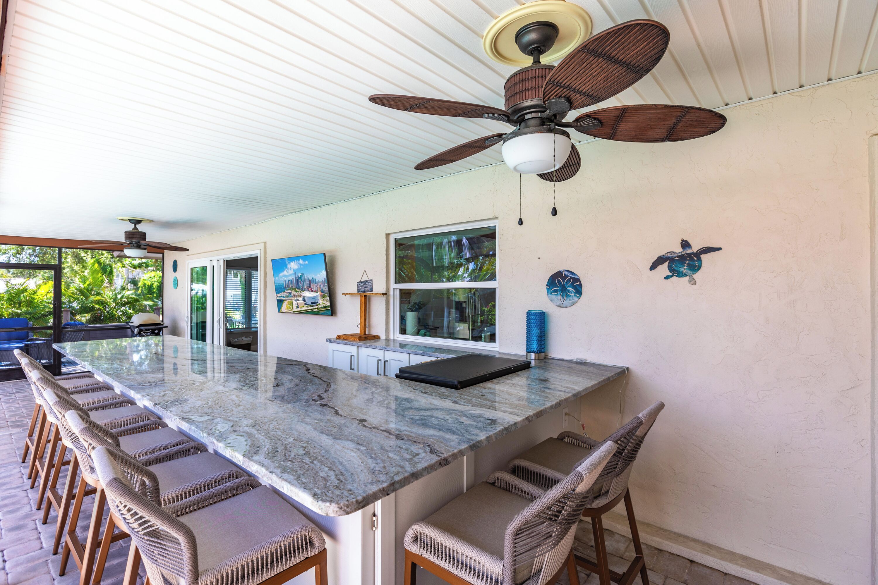 A spacious kitchen with a large island, bar stools, and a ceiling fan.