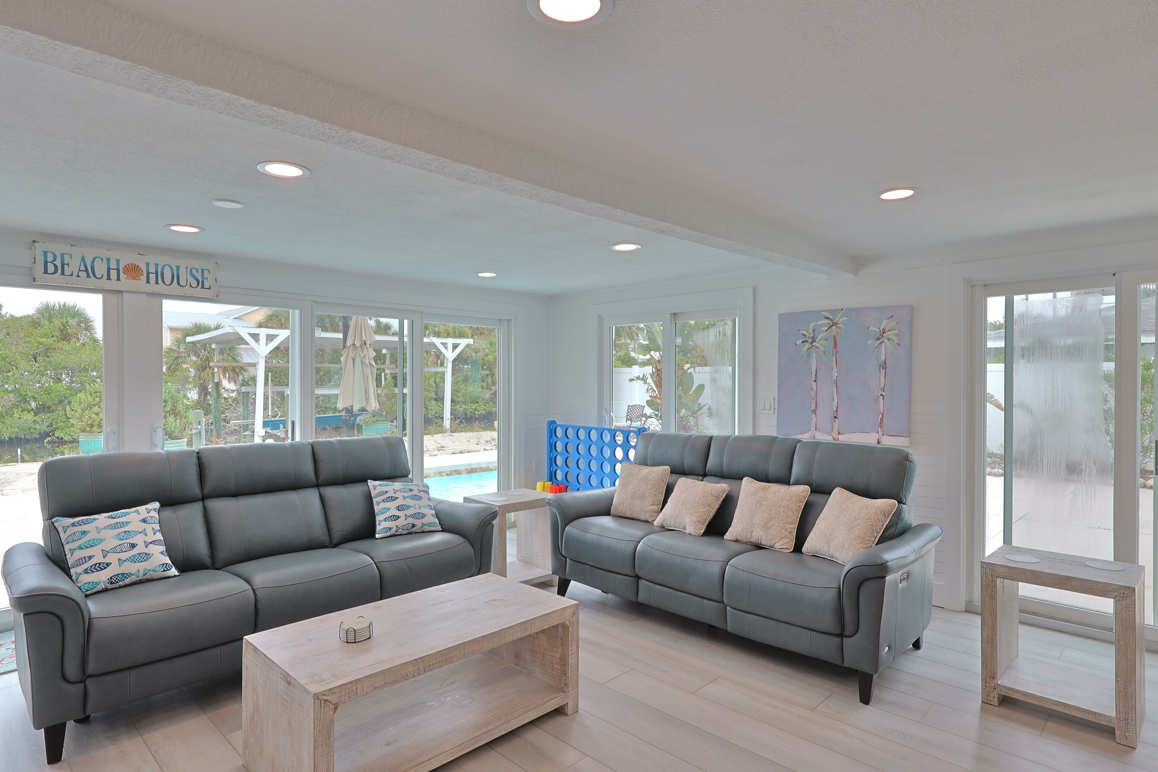 A spacious living room with two grey sofas, a wooden coffee table, and a large window overlooking a pool area.