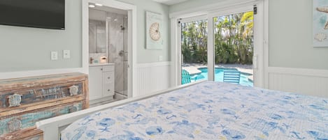 A bedroom with a bed, a dresser, a TV, and a door leading to a pool area.