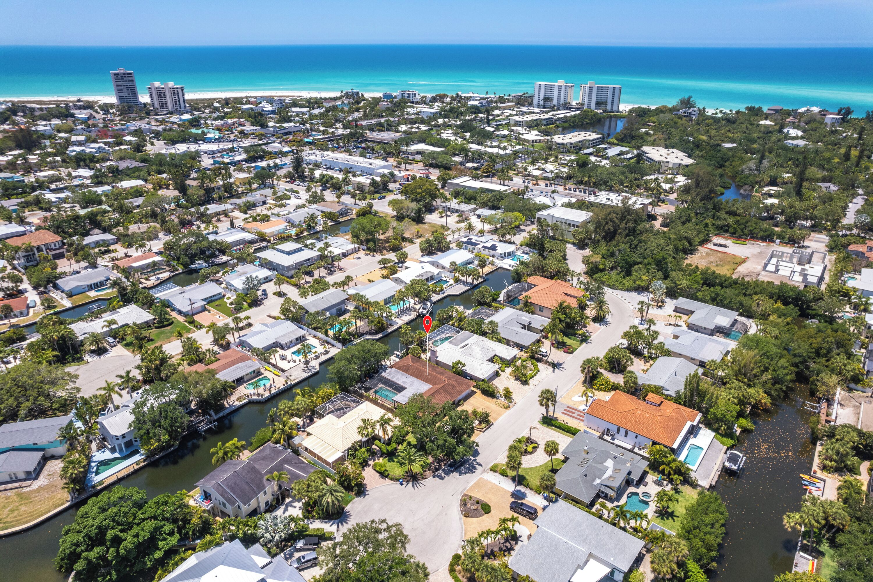 An aerial view of a residential area with houses, a river, and a beach in the background.