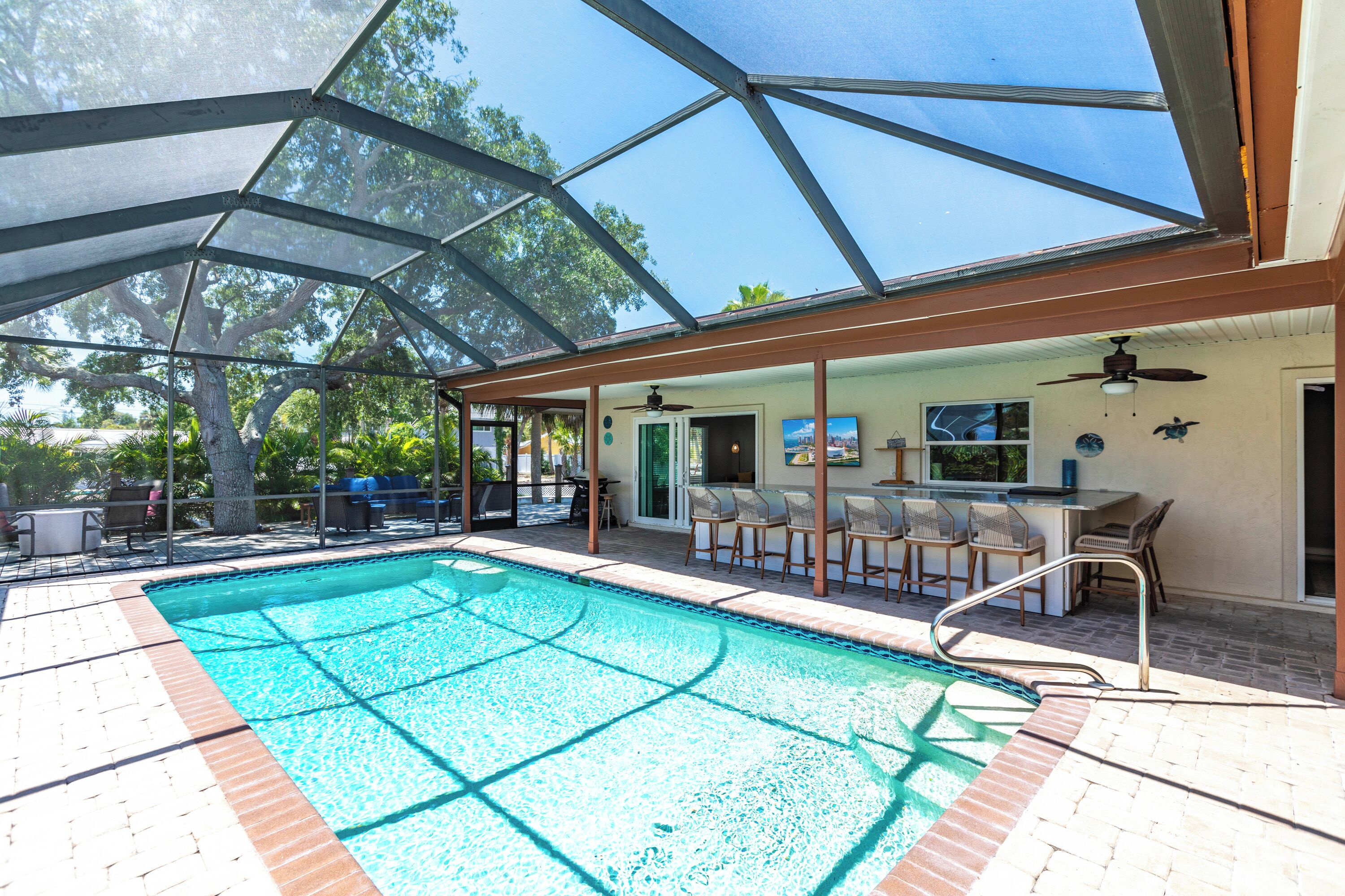 An indoor swimming pool with a glass ceiling, surrounded by lounge chairs and a bar area.