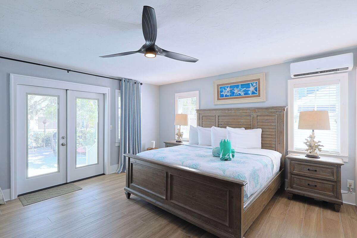 A bedroom with a bed, nightstands, a ceiling fan, and a window with blinds.