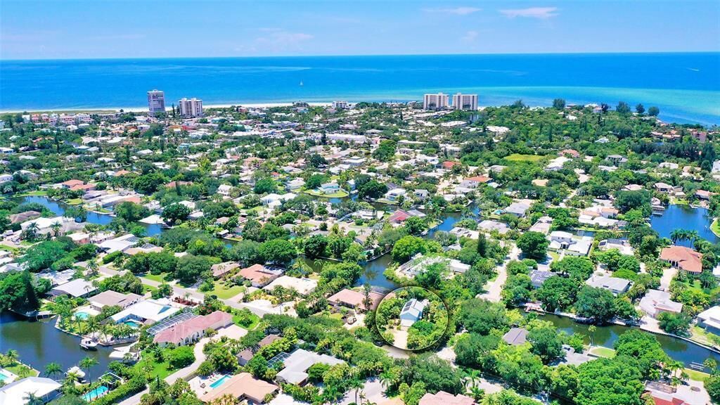 An aerial view of a coastal residential area with houses, a river, and a beach.