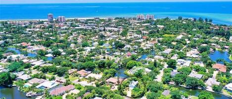 An aerial view of a coastal residential area with houses, a river, and a beach.