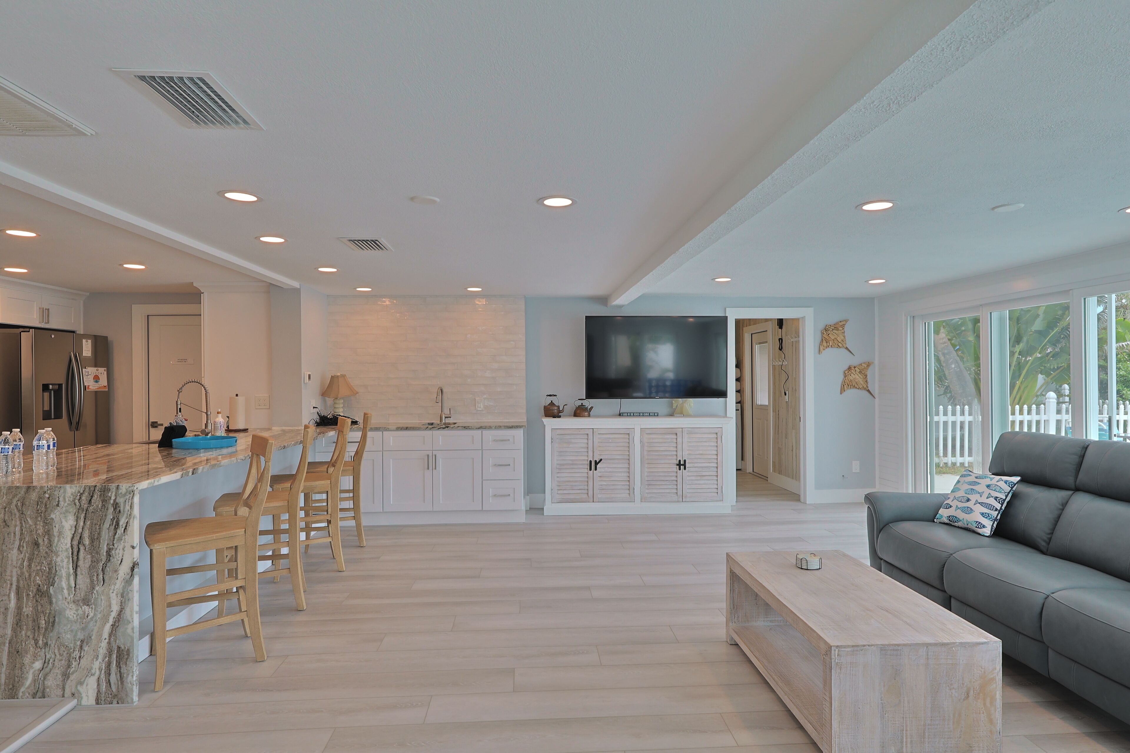 Una cocina moderna con una isla de mármol, taburetes de madera y un televisor integrado.