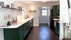 Une cuisine moderne avec des meubles verts, un plan de travail blanc et un plancher en bois.