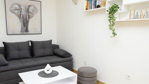 Un salón moderno con un sofá gris, una mesa de centro blanca y un otomano gris.