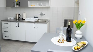Una cocina moderna con armarios blancos, un lavamanos de acero inoxidable y una zona de comedor con mesa blanca.