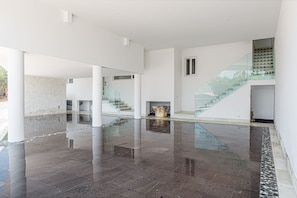 A spacious lobby with a polished floor, a staircase with glass railings, and a large vase on a pedestal.
