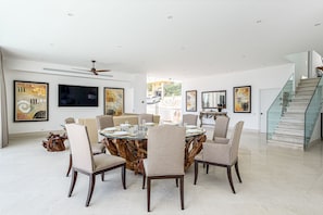 A modern dining area with a round table, six chairs, and artwork on the walls.