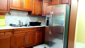 A kitchen with wooden cabinets, a stainless steel refrigerator, a sink, and a dish drying rack. - SUNFLOWER LANE- OCEAN/ISLAND VIEW APARMENT 2BDR 2BTH - 7 mins from Capital/Beach (Road Town)