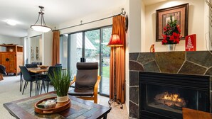 Ein gemütliches Wohnzimmer mit Kamin, ein Essbereich mit Tisch und Stühlen sowie ein großes Fenster mit Vorhängen.