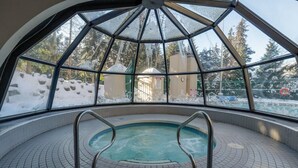 An indoor swimming pool with a view of a snowy landscape through large windows. - The Maple | Ski-in Ski-out 1 Bed w/ Hot Tub, Pool, Sauna, and Fireplace (Whistler)