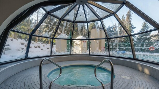 Ein Hallenbad mit Blick auf eine verschneite Landschaft durch große Fenster.