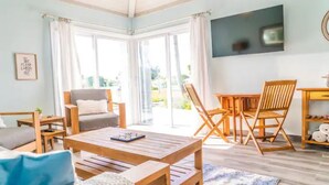 Un salón espacioso con una mesa de centro de madera, un sofá y un televisor montado en la pared.
