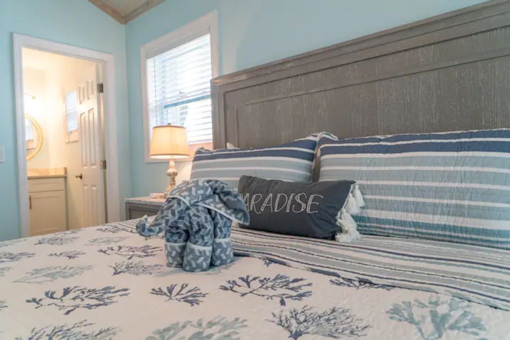 A bedroom with a bed, a nightstand, a lamp, and a door.