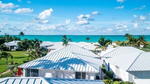 Un resort con edificios de techo blanco, vista al océano y palmeras.