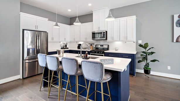 A modern kitchen with white cabinets, stainless steel appliances, and blue bar stools. - Your lavish contemporary duplex | downtown Houston| Rooftop. (Houston)