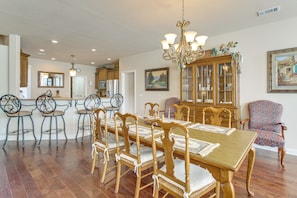 A dining area with a wooden table and chairs, a chandelier, and a cabinet with glass doors.