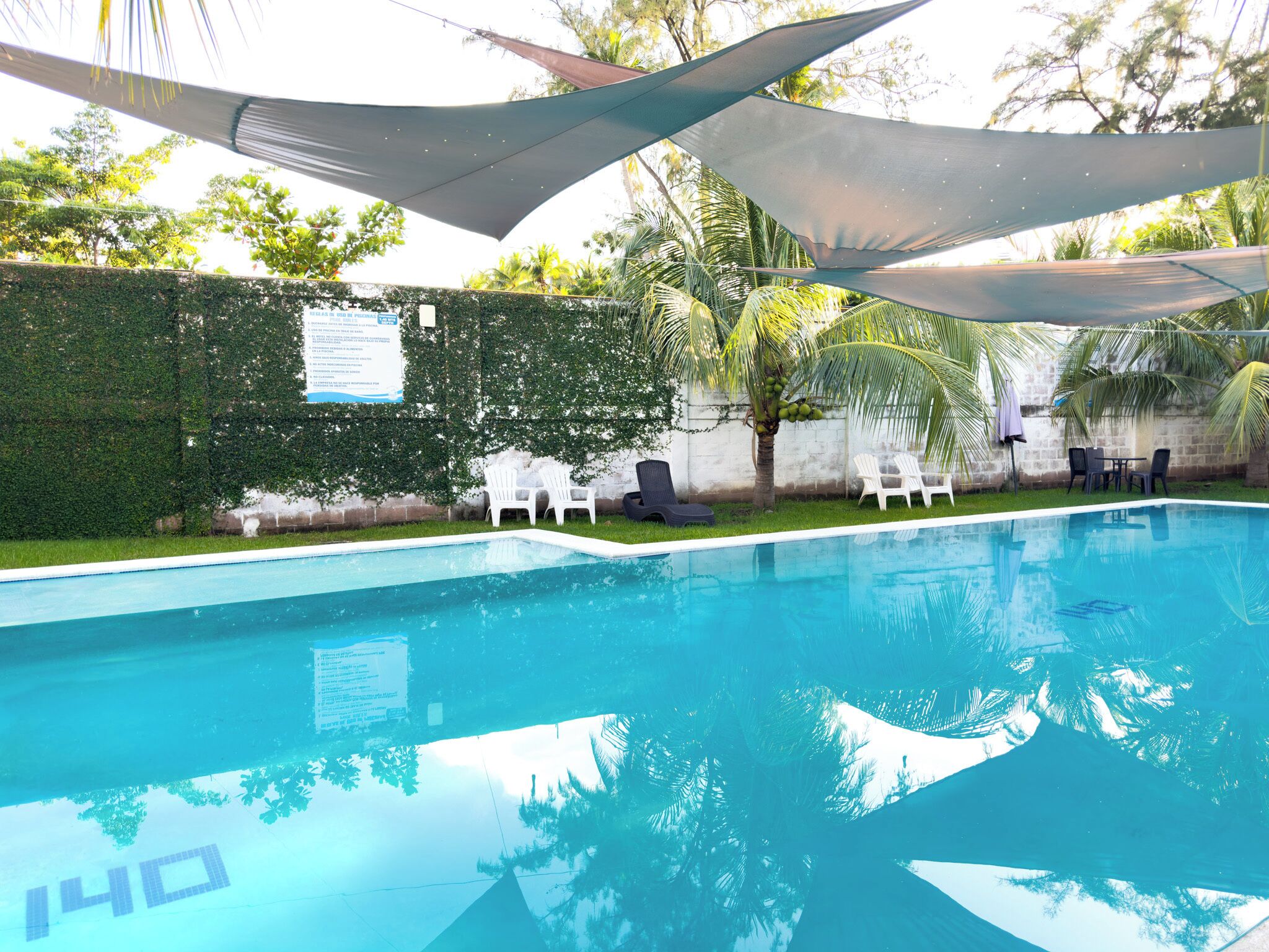 Una piscina al aire libre, sombrillas, sillones reclinables de piscina